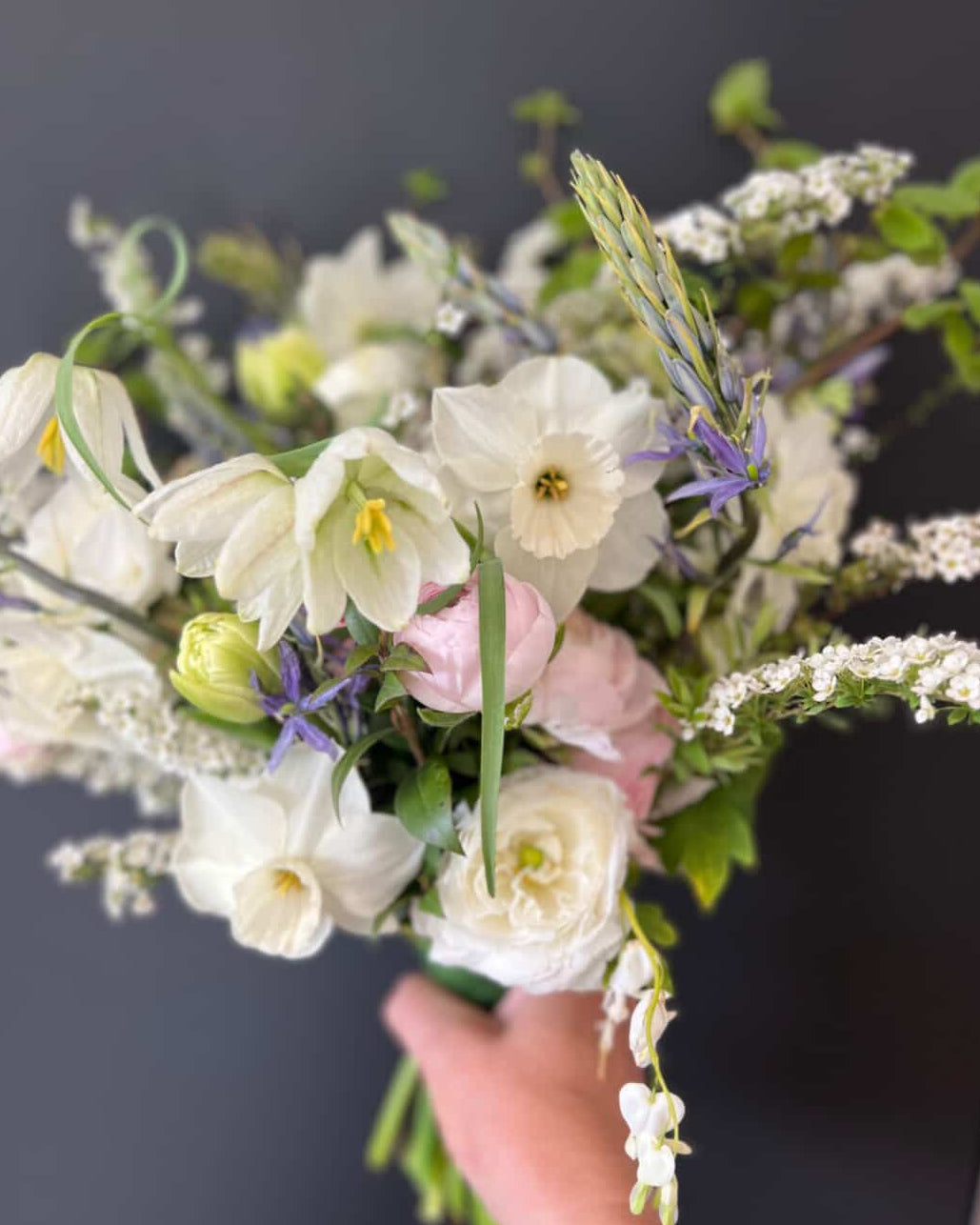 Bouquet of flowers held by a hand against a dark background