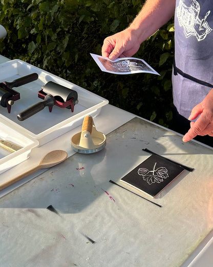 Person working on a craft project at an outdoor table with tools and materials.